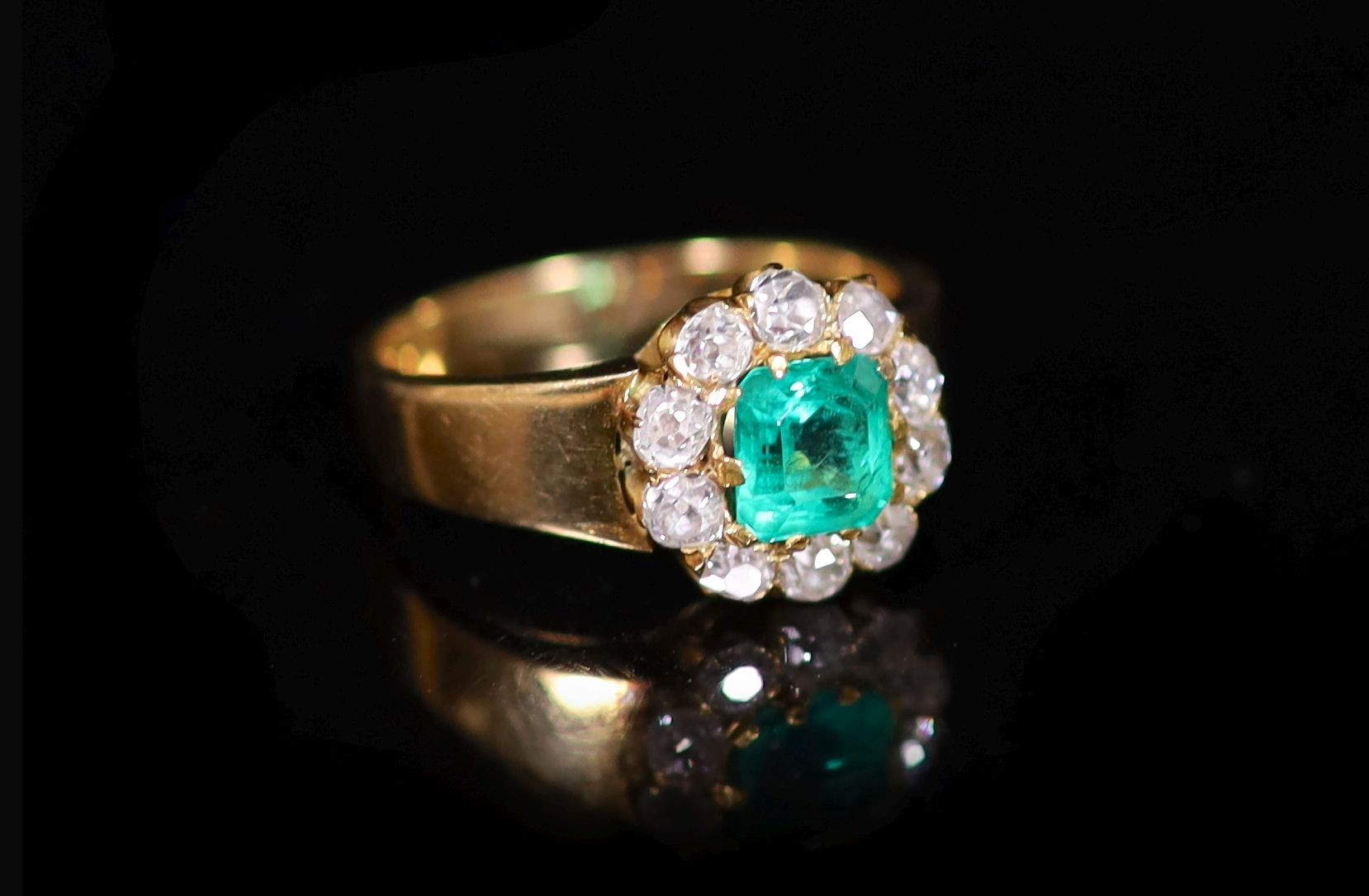 A gold, emerald and old cut diamond set circular cluster ring